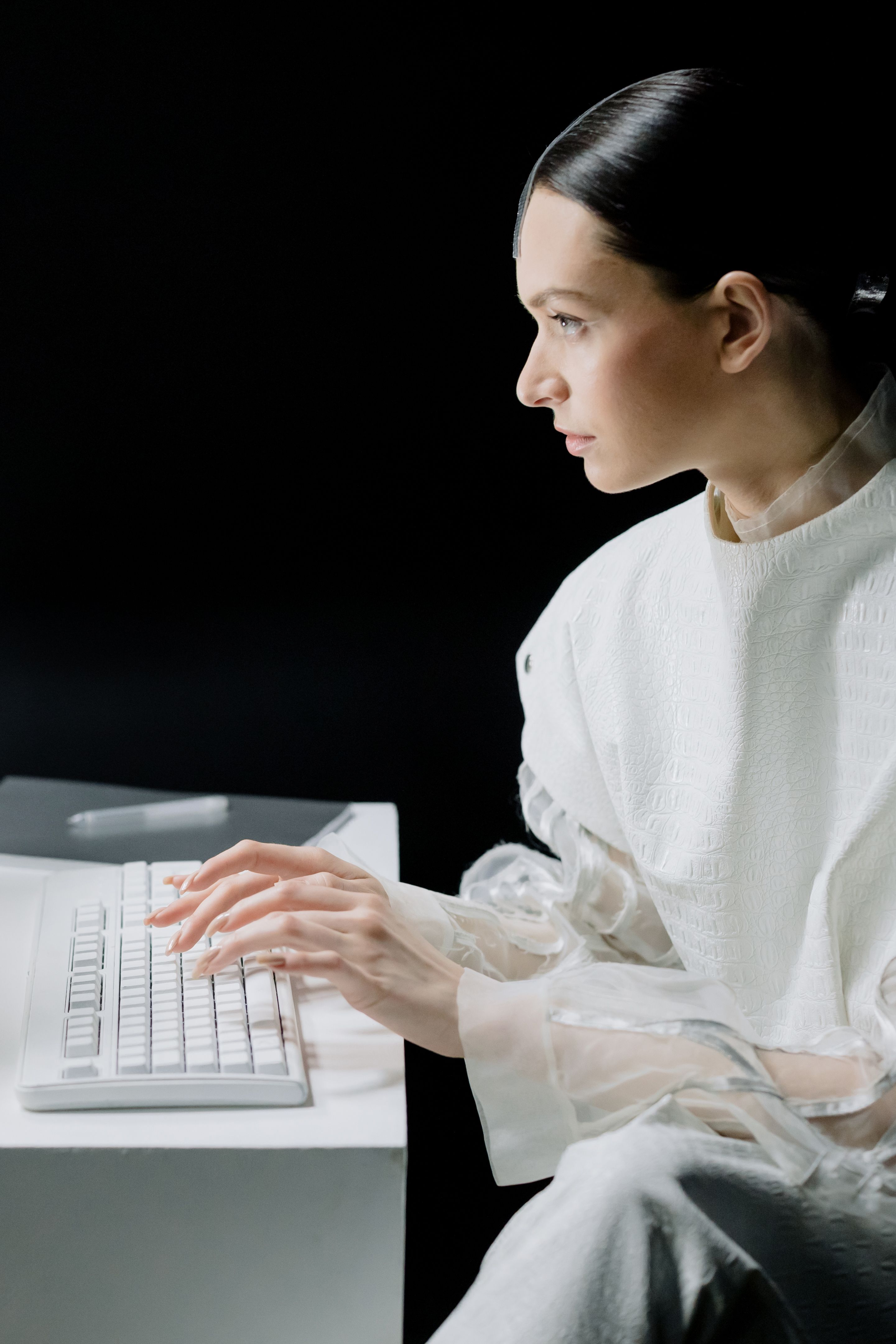 A person in profile typing at a keyboard