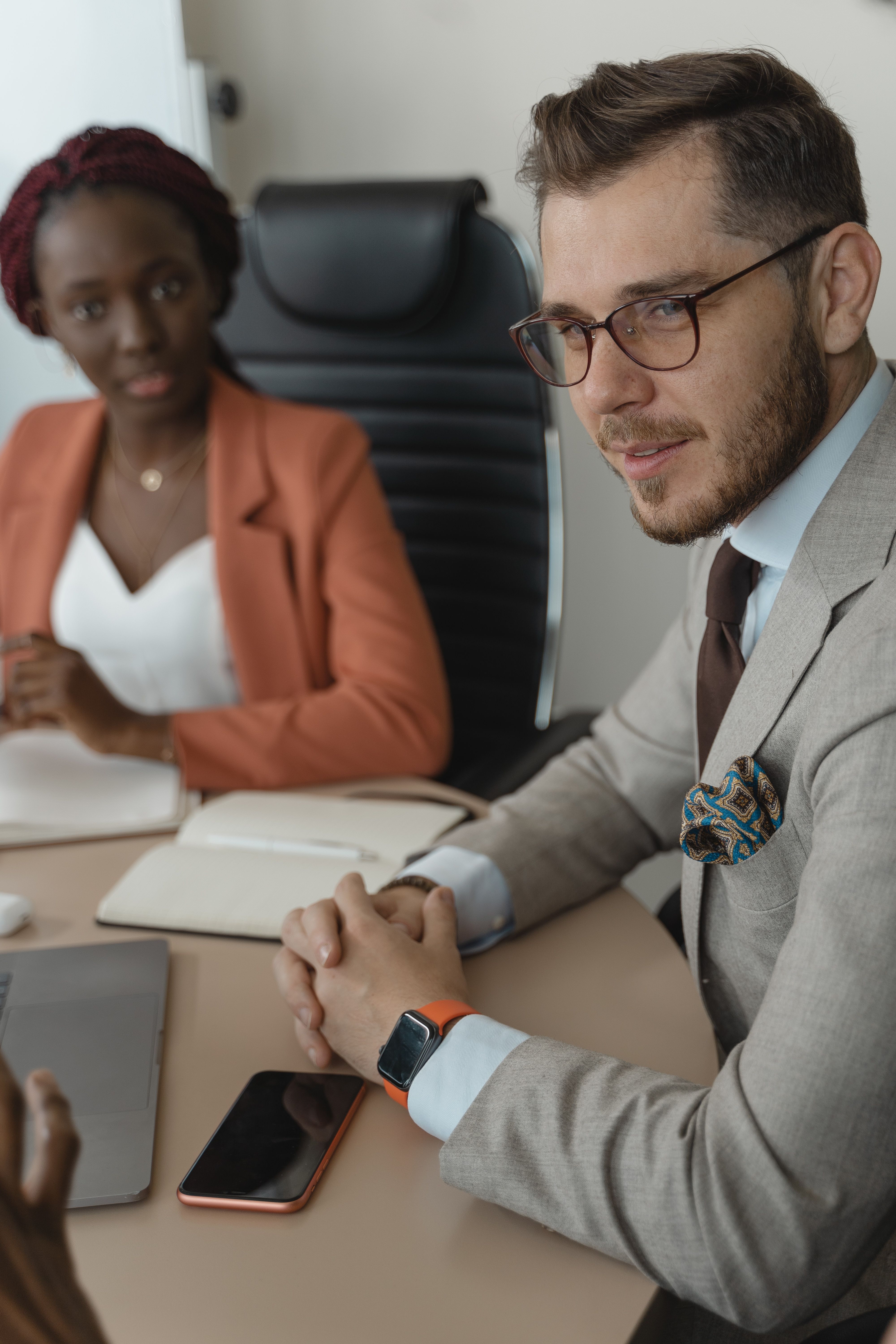 Two colleagues in a meeting, one speaking across a conference table